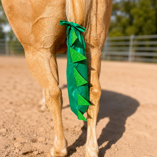 Horse with a green dinosaur tailbag on a dirt ground