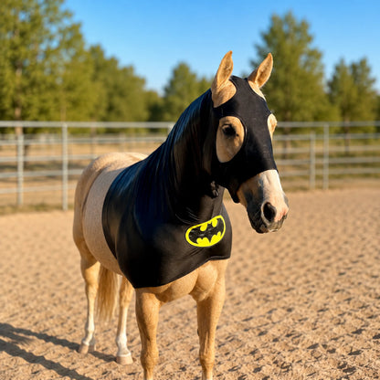Horse wearing a black hood sleazy with a Batman logo in an outdoor setting