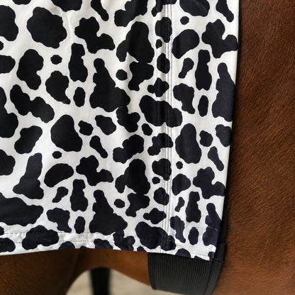 Close-up of a belly view from black and white cow print hood sleazy on a fabric surface.