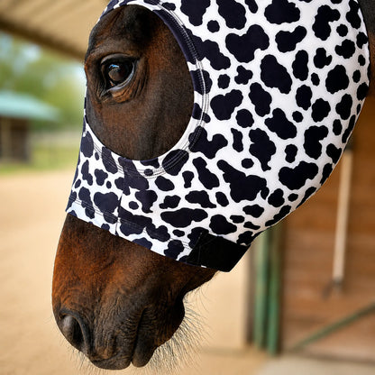 Horse wearing a black and white cow hood sleazy in an outdoor setting.
