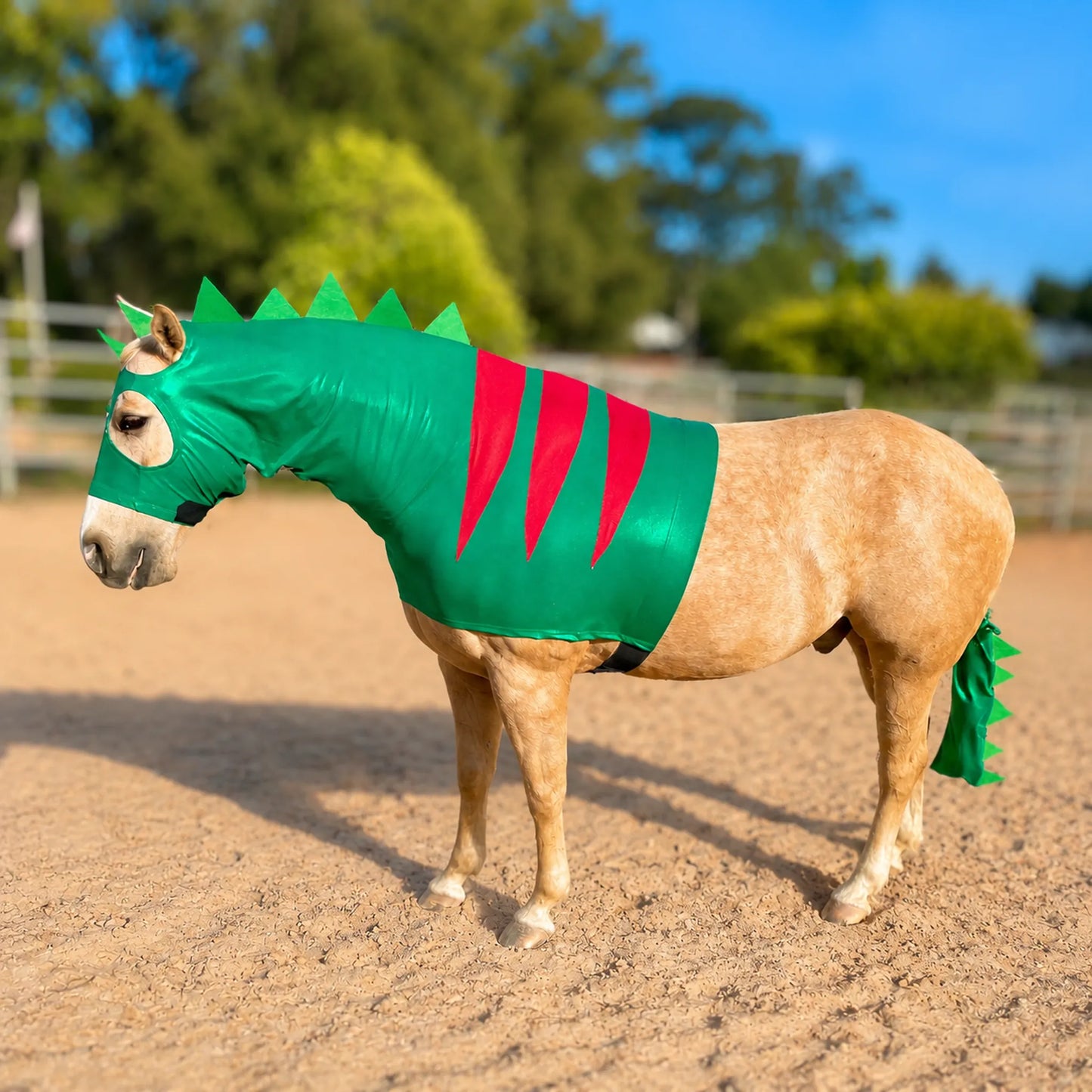 Horse wearing a green dinosaur costume sleazy with spiky details in an outdoor setting.