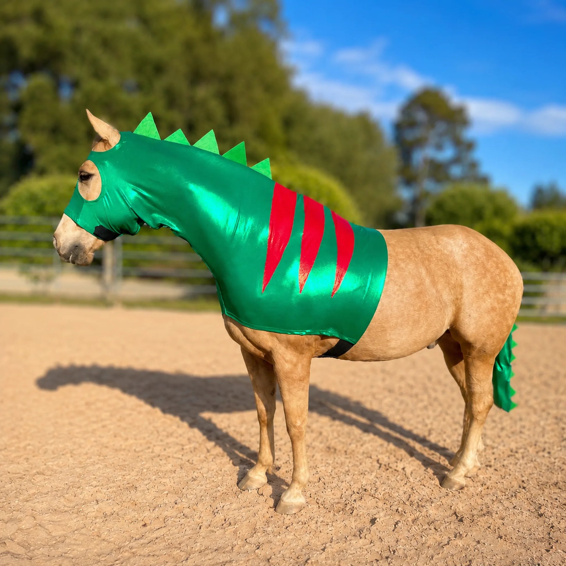 Horse wearing a green dinosaur costume sleazy with red stripes in an outdoor setting