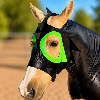 Horse wearing a black train your dragon horse costume sleazy with green straps in an outdoor setting