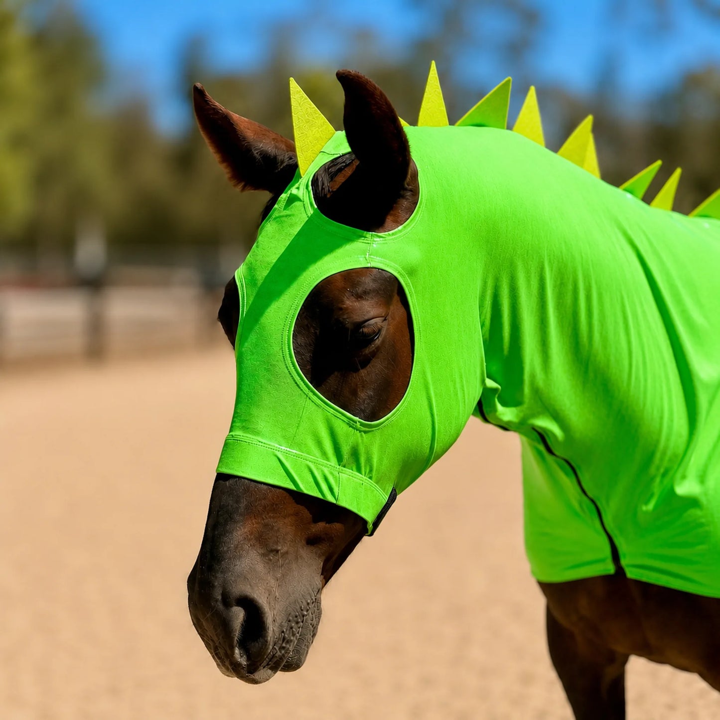 Horse wearing a bright metallic green dragon horse costume sleazy with spikes and matching tailbag spiky details in an outdoor setting.