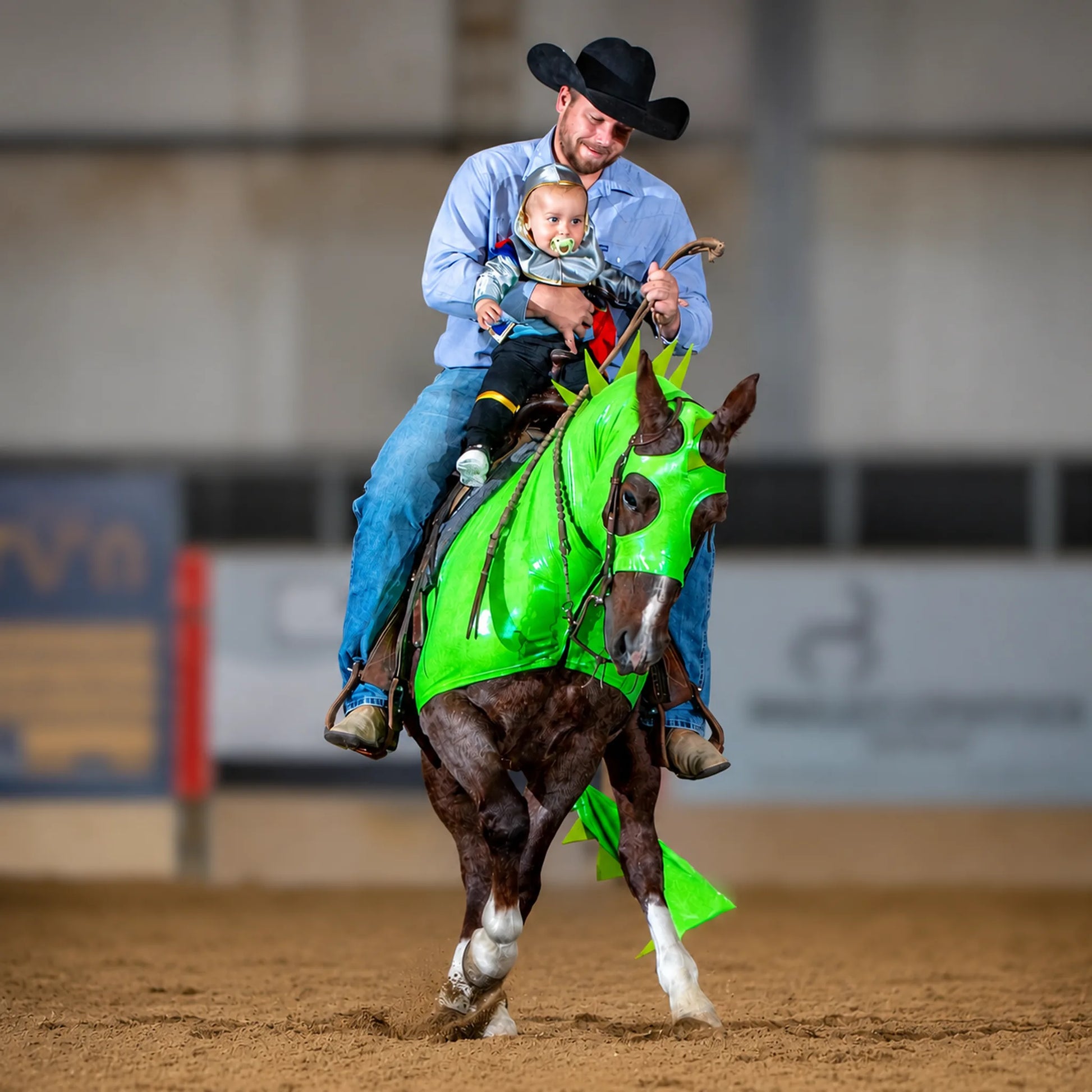 Man riding a metallic green dragon horse costume sleazy with matching tailbag in a rodeo setting