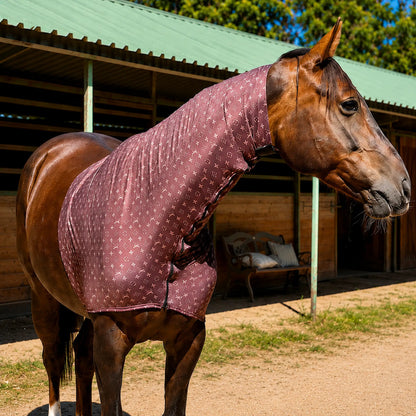 Horse wearing a LV brown faceless sleazy hood standing in front of a stable.