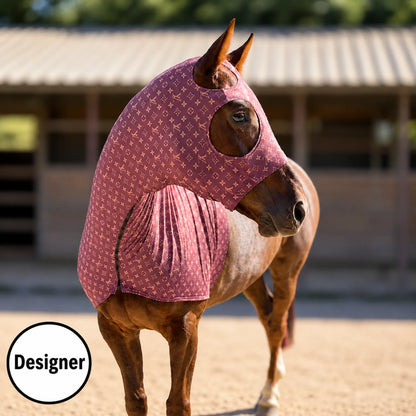 A brown horse standing in a sandy outdoor stable area wearing a fitted horse LV brown sleazy hood. The LV brown hood is showing the front view.