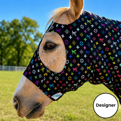A close-up of a horse outdoors wearing a LV color sleazy hood. The background shows a grassy field and trees under a blue sky.