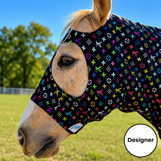 A close-up of a horse outdoors wearing a LV color sleazy hood. The background shows a grassy field and trees under a blue sky.