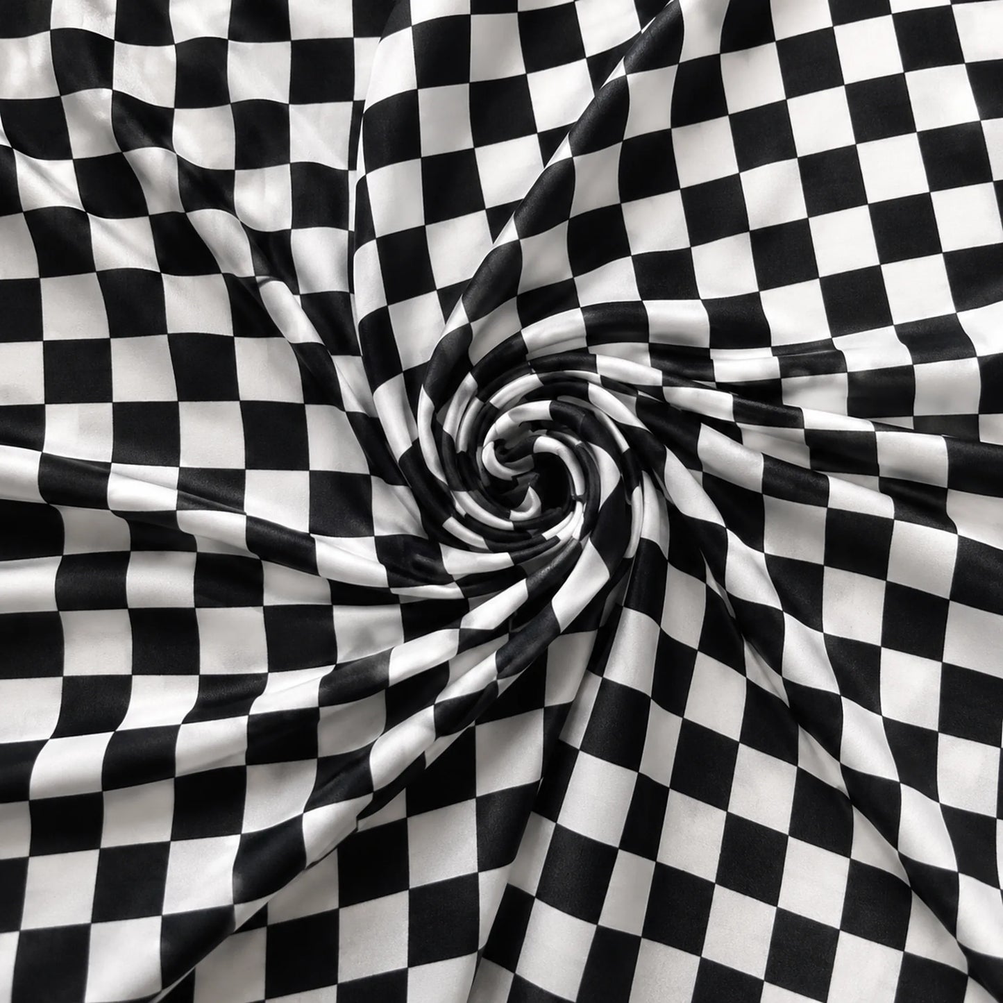 Black and white checkered fabric draped in a spiral pattern, showing a smooth texture and glossy finish.